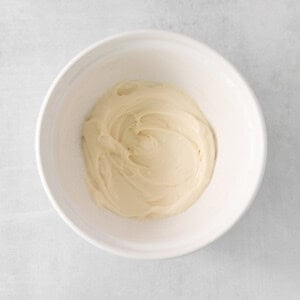 whipped cream in a bowl on a white surface.