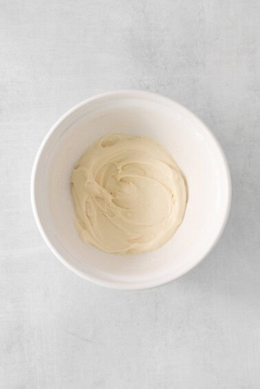 whipped cream in a bowl on a white surface.