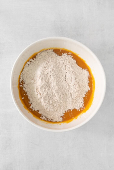a white bowl filled with flour on a white surface.