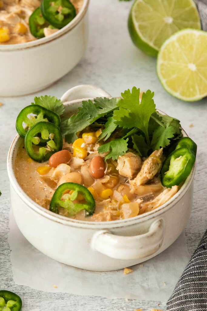 a bowl of chicken enchilada soup with limes and jalapenos.