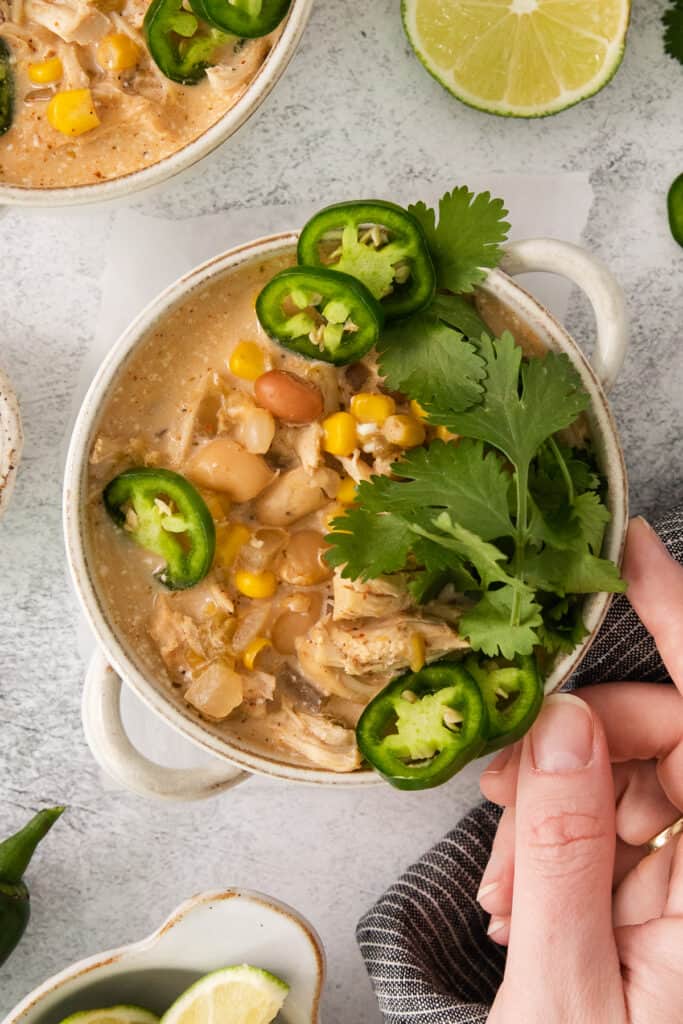 a bowl of mexican chicken soup with limes and jalapenos.