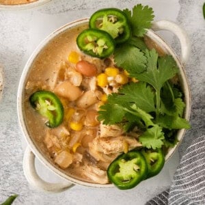 a bowl of mexican chicken soup with limes and jalapenos.