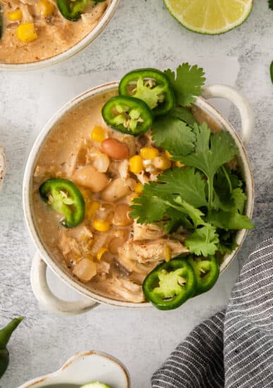 a bowl of mexican chicken soup with limes and jalapenos.