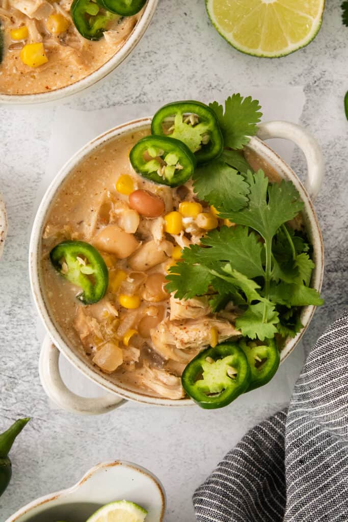 a bowl of mexican chicken soup with limes and jalapenos.