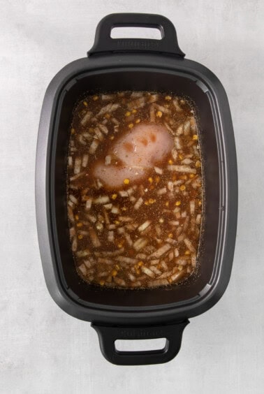 a slow cooker filled with chicken and vegetables.