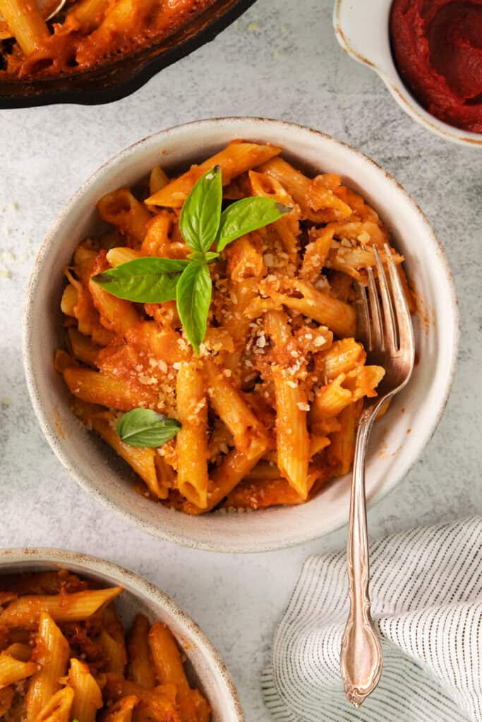 a white bowl filled with pasta and sauce.