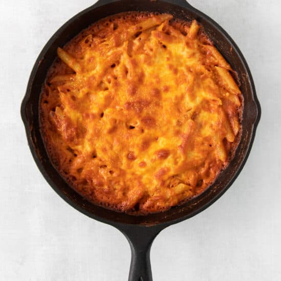 a skillet with a cheesy dish inside of it.