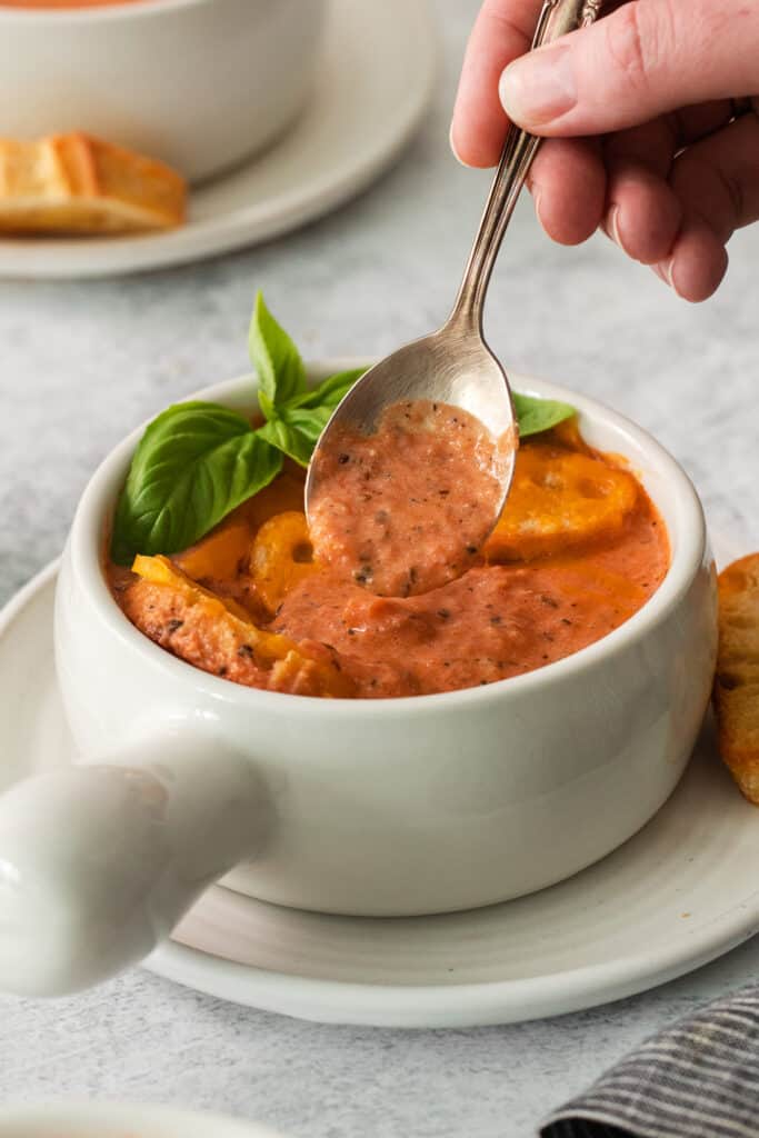a spoonful of tomato soup in a white bowl.