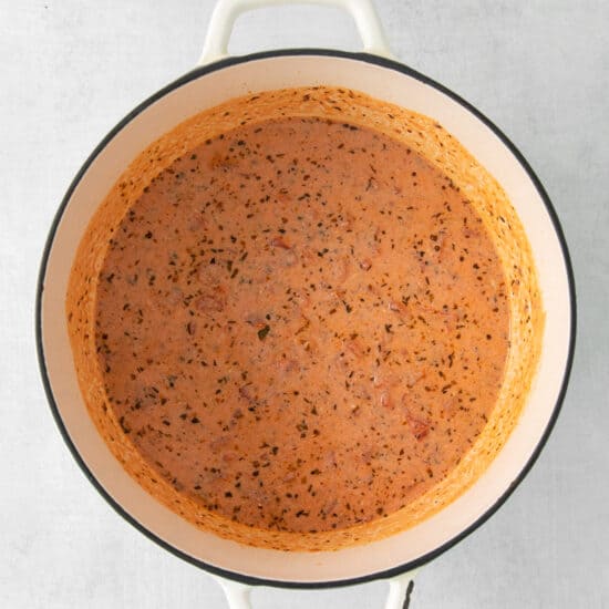 a pot filled with red sauce on a white background.