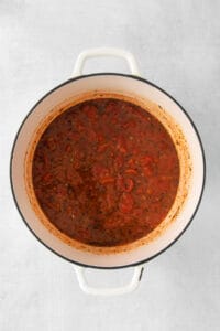 a pot full of tomato sauce on a white background.