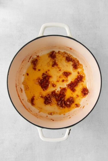 a pot with a sauce in it on a white background.