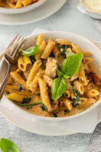 a bowl of pasta with spinach and meat.