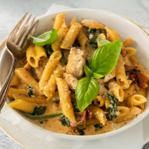 a bowl of pasta with spinach and meat.