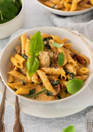 a bowl of pasta with meat and spinach.