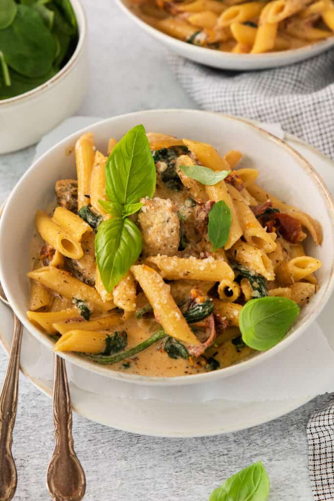 a bowl of pasta with meat and spinach.
