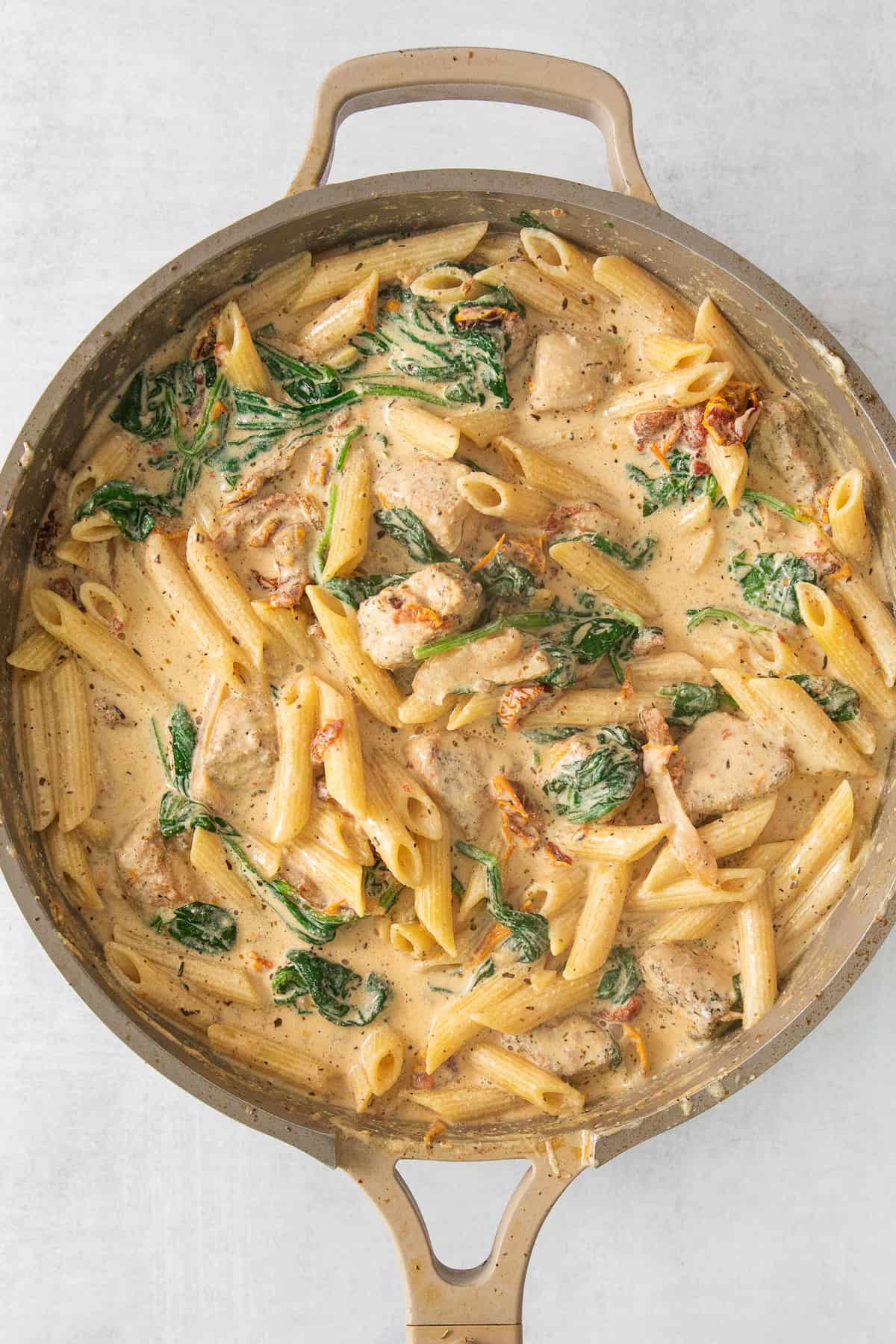 chicken and spinach pasta in a skillet.