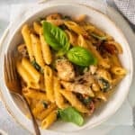a bowl of pasta with chicken and spinach.
