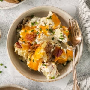 a bowl of potato salad with bacon and sour cream.