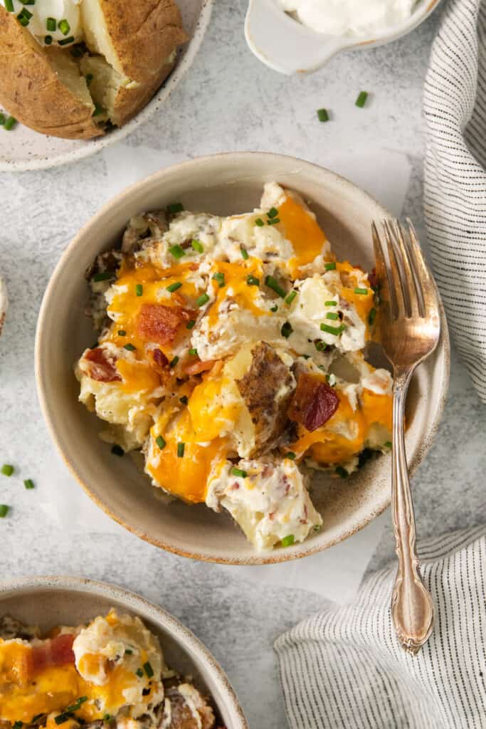 a bowl of potato salad with bacon and sour cream.
