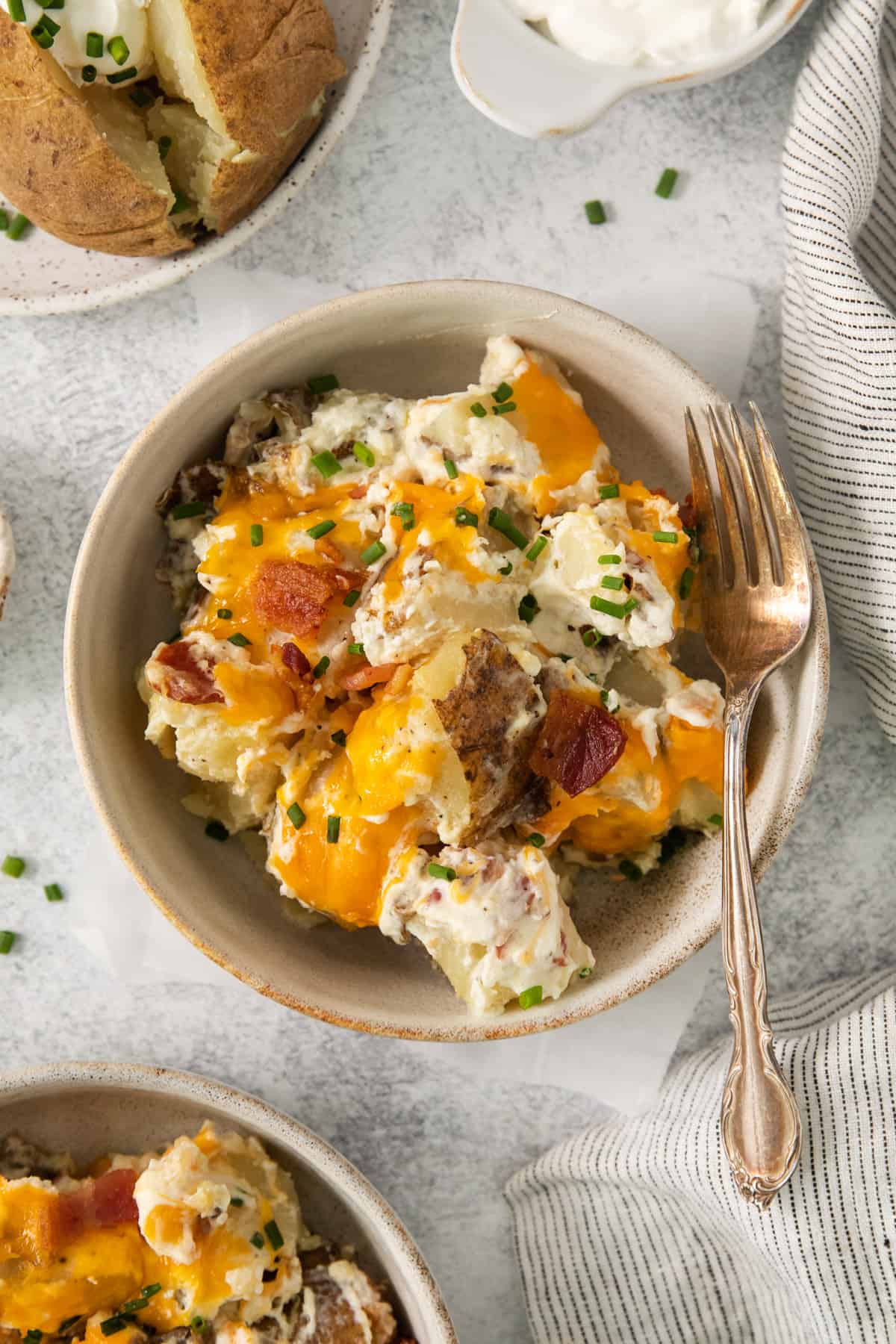 a bowl of potato salad with bacon and sour cream.