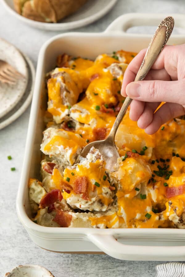 a person taking a spoon out of a casserole dish.