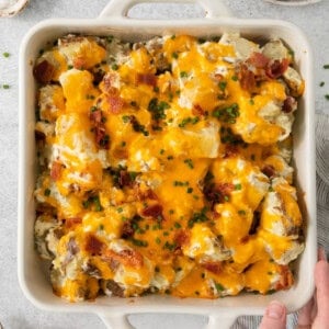 cheesy potato casserole in a white baking dish.