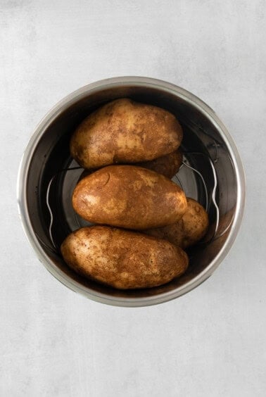 roasted potatoes in a metal bowl on a white background.