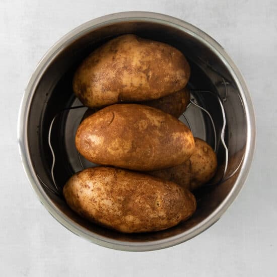roasted potatoes in a metal bowl on a white background.