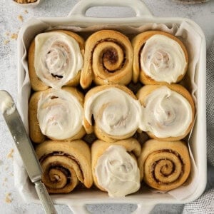 a pan filled with cinnamon rolls next to a glass of milk.