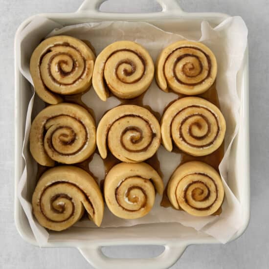 a white container filled with cinnamon buns on top of a table.