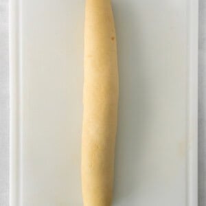 a long piece of bread sitting on top of a cutting board.