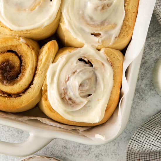 a tray filled with cinnamon rolls covered in icing.