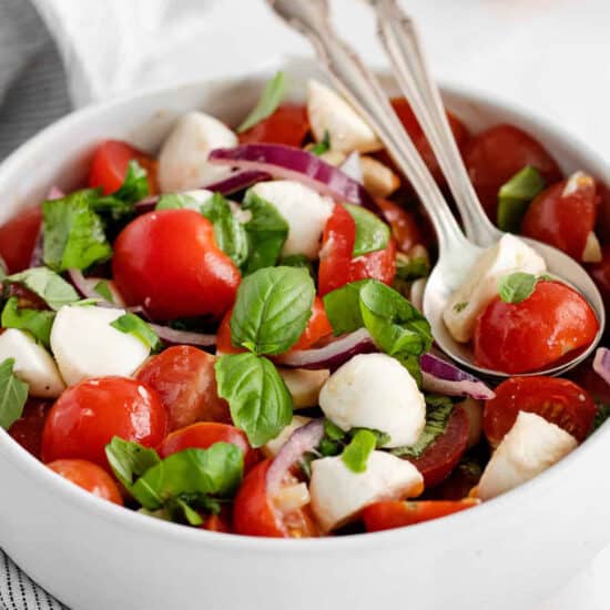 a salad with tomatoes, mozzarella, onions and basil.