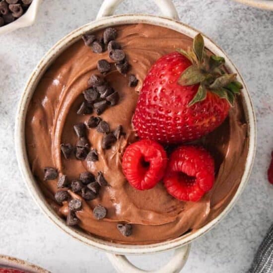 a bowl of chocolate pudding with a strawberry and chocolate chips.