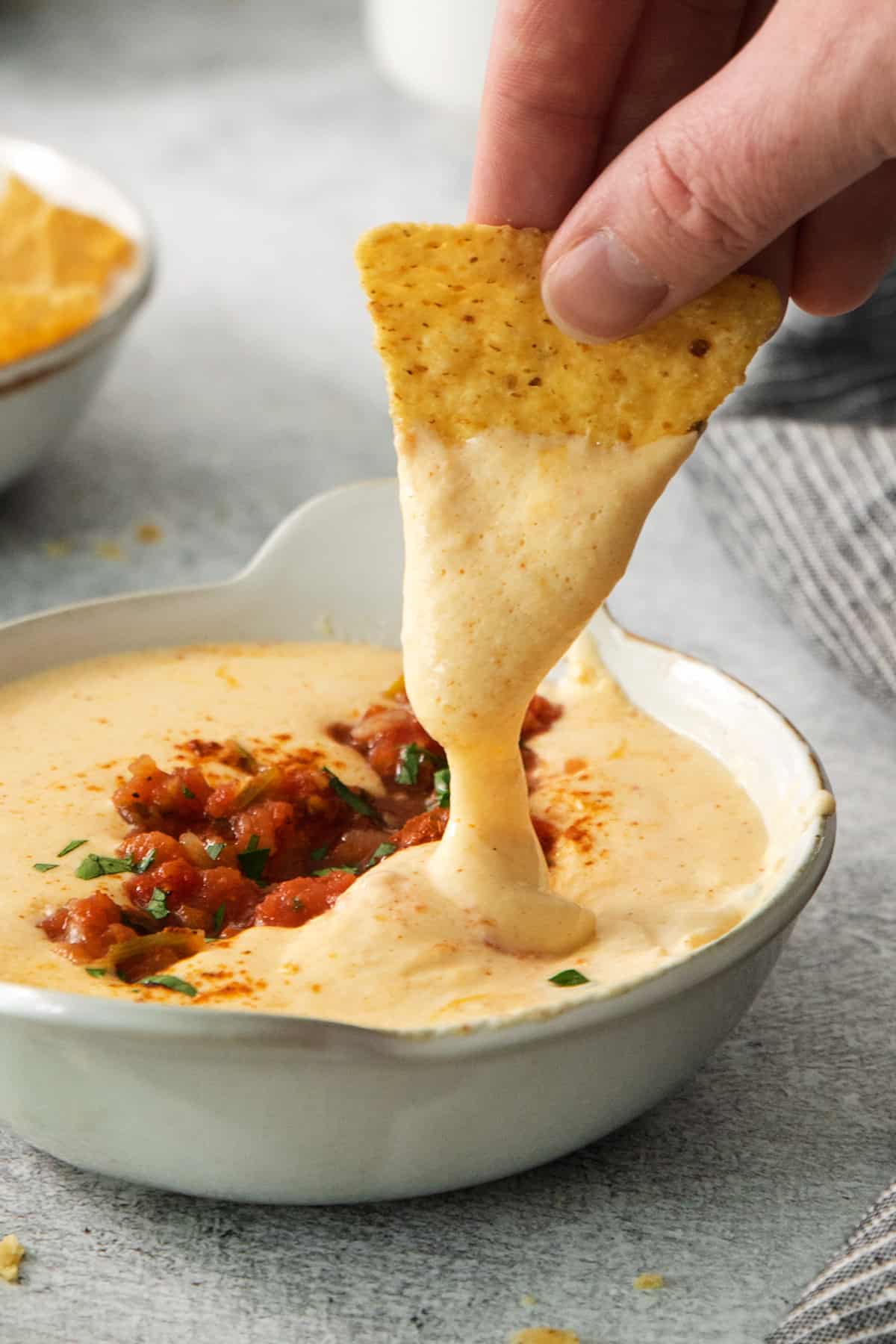 a person dipping a tortilla into a bowl of dip.