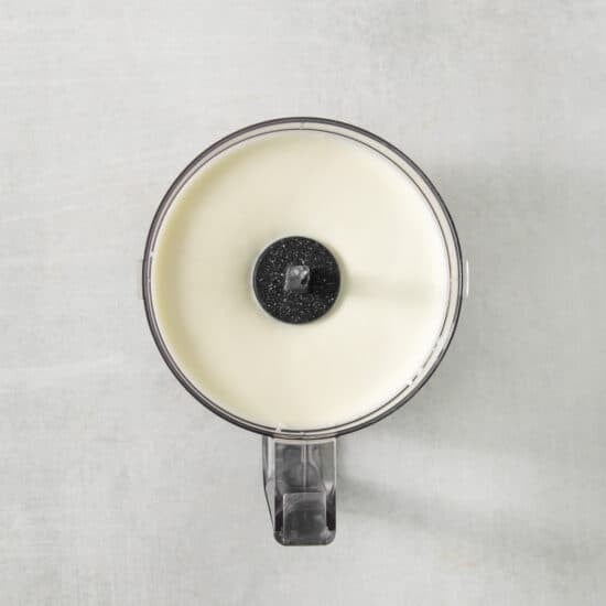 a white candle with a black lid sitting on a white surface.