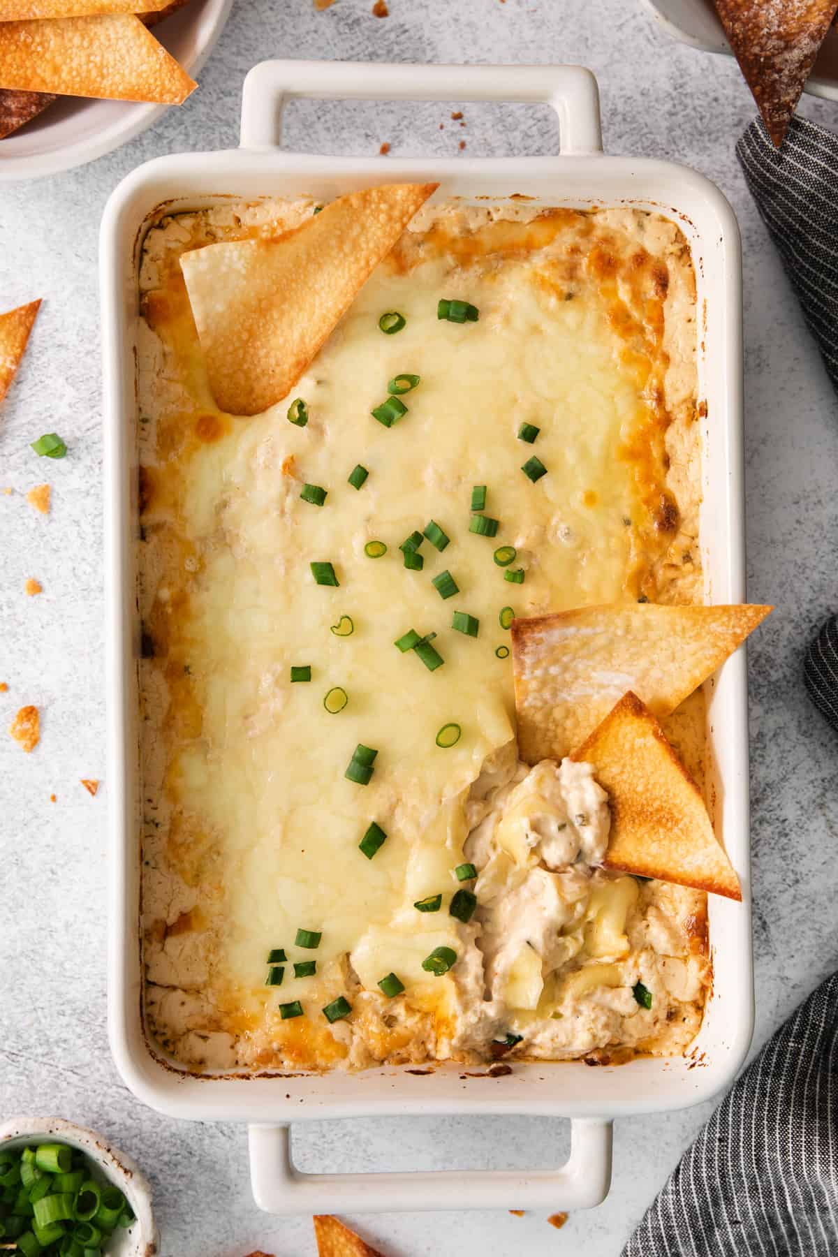 cheesy chicken dip in a white dish with chips.