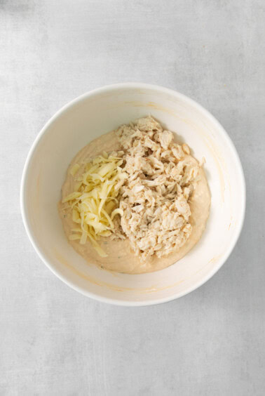 a white bowl with cheese and chicken in it.