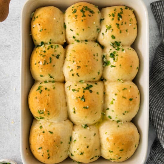 cheesy garlic rolls in a baking dish with butter and parsley.