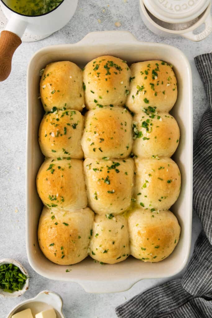 cheesy garlic rolls in a baking dish with butter and parsley.