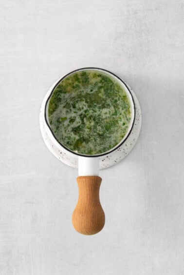 a bowl of green soup with a wooden spoon.