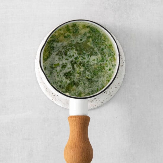 a bowl of green soup with a wooden spoon.