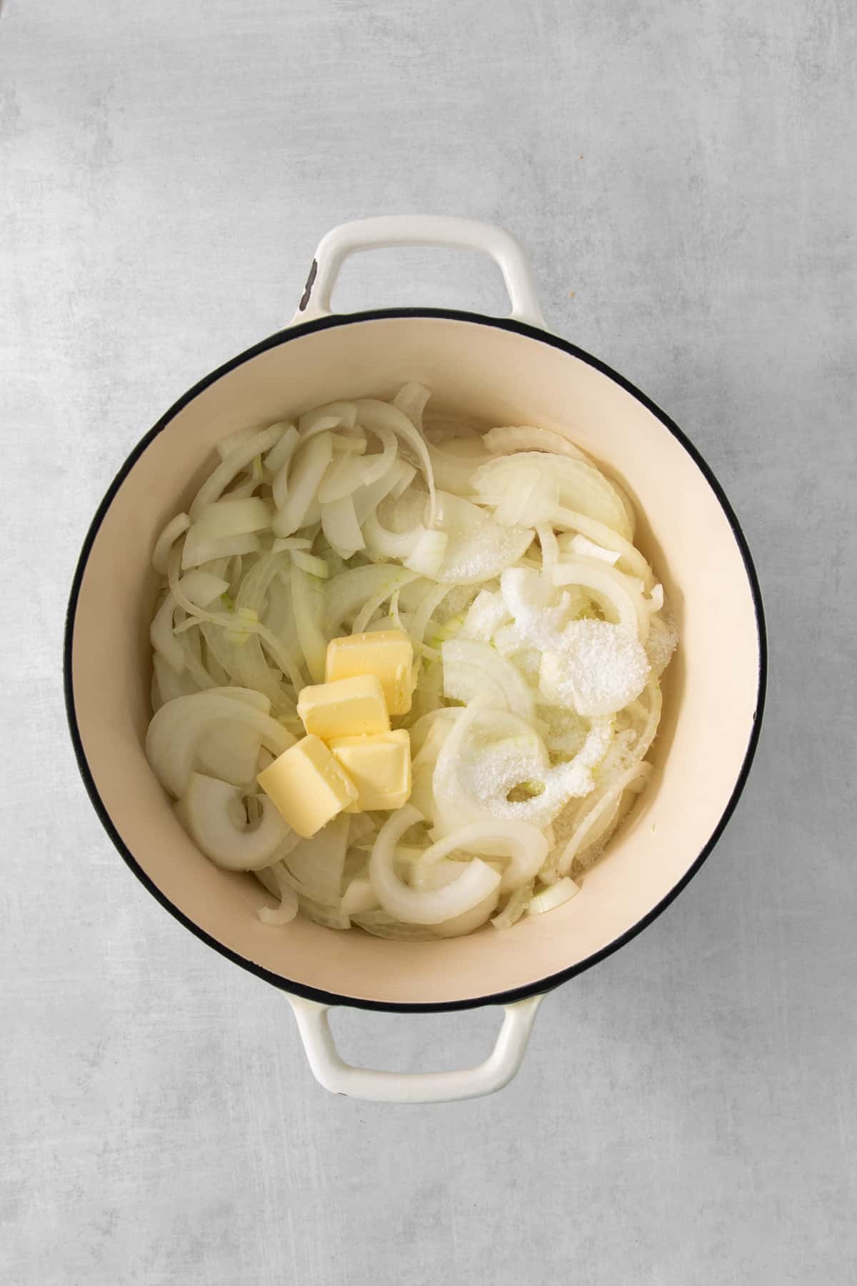 onion and butter in a pot on a grey background.