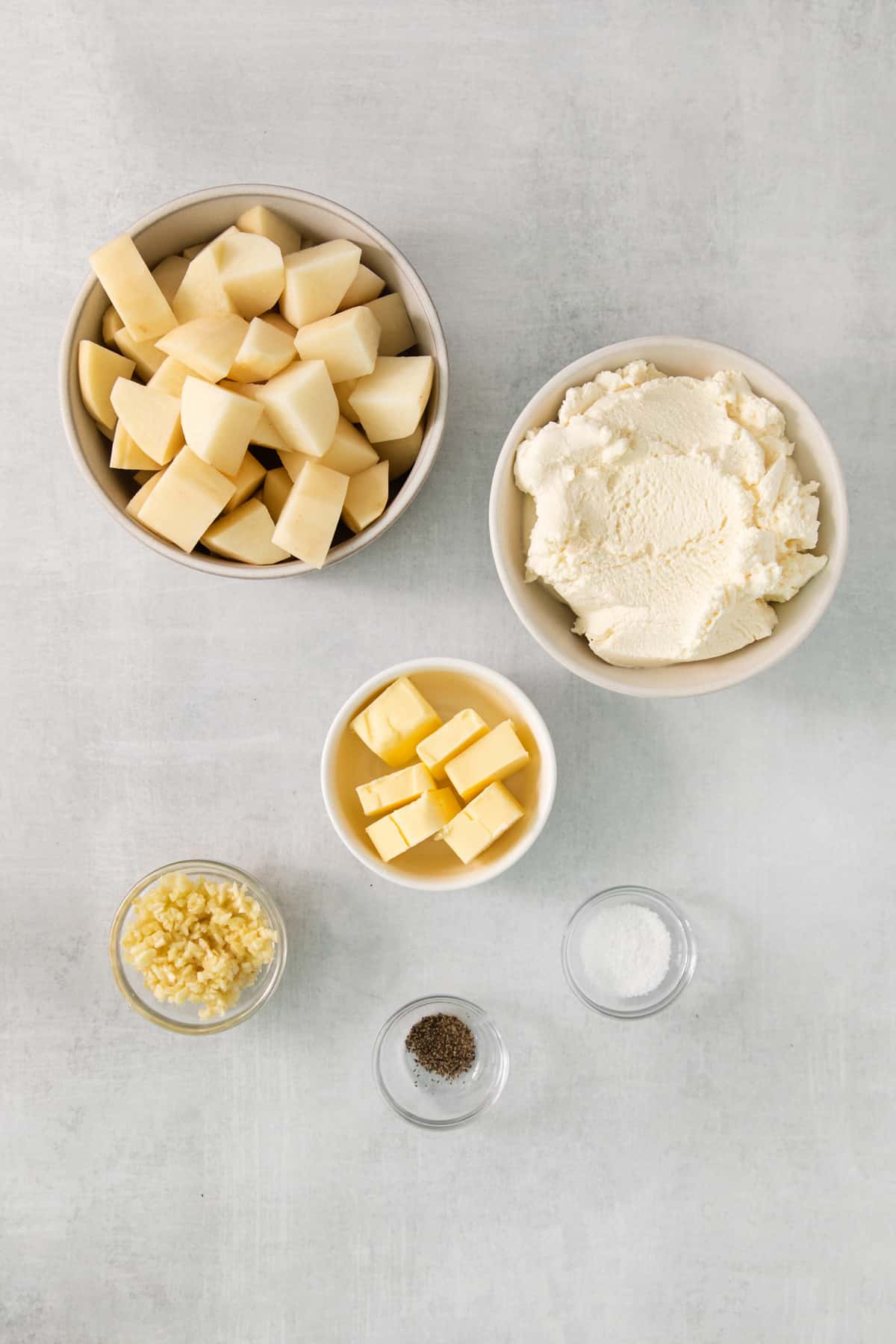 A bowl of cheese, butter, salt, and other ingredients on a gray background.