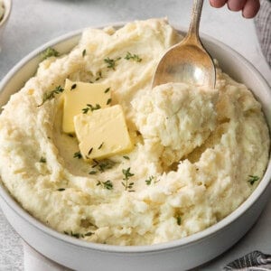 Mashed potatoes in a bowl with butter and thyme.