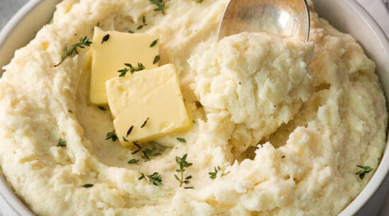 Mashed potatoes in a bowl with butter and thyme.