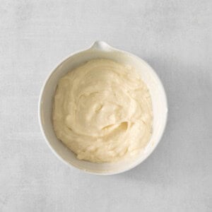 whipped cream in a white bowl on a gray background.