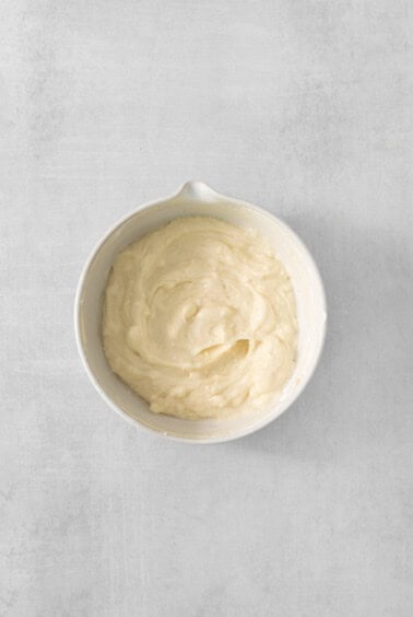 whipped cream in a white bowl on a gray background.