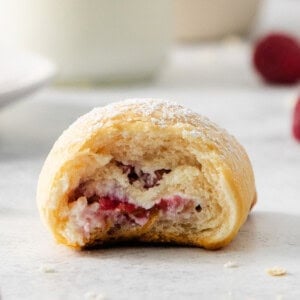 a raspberry pastry with a bite taken out of it.