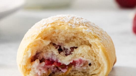 a raspberry pastry with a bite taken out of it.